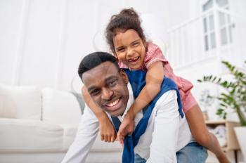 Smiling father and little daughter poses in living room. Dad and female child leisures in their house together, good relationship