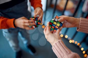 People play with puzzle cubes, intellectual rest. Toy for brain and logical mind training, creative game, solving of complex problems