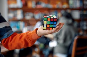 Young boy shows colorful puzzle cube in his hand. Toy for brain and logical mind training, creative game, solving of complex problems
