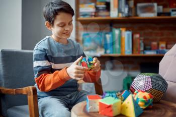 Young boy holds colorful puzzle cube in his hand. Toy for brain and logical mind training, creative game, solving of complex problems