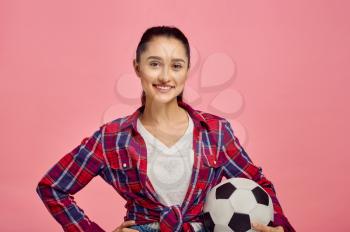 Young pretty woman with football ball, pink background. Face expression, female person poses in studio, genre concept, occupation or hobby