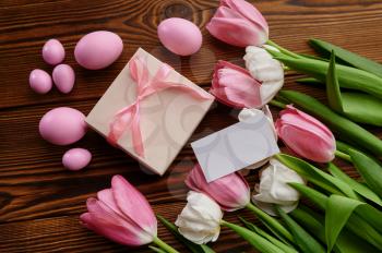 Pink tulips, easter eggs and gift box on wooden background. Spring flowers blooming and paschal food, fresh floral decoration, holiday celebration symbol