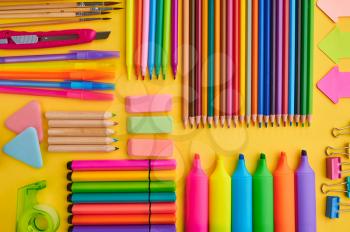 Office stationery supplies, yellow background. School or education accessories, writing and drawing tools, pencils and rubbers, brushes and pens