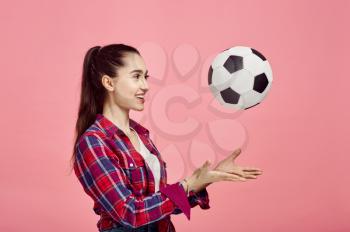 Portrait of young woman with football ball, pink background. Face expression, female person poses in studio, genre concept, occupation or hobby