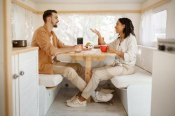 Love couple having breakfast in rv, camping in a trailer. Man and woman travels on van, romantic vacations on motorhome, campers leisures in camping-car