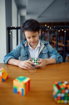 Little boy trying to solve puzzle cubes. Toy for brain and logical mind training, creative game, solving of complex problems