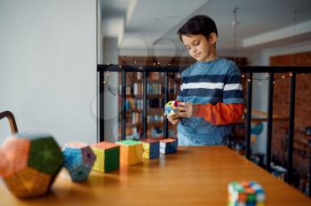 Thoughtful little boy play with puzzle cubes. Toy for brain and logical mind training, creative game, solving of complex problems