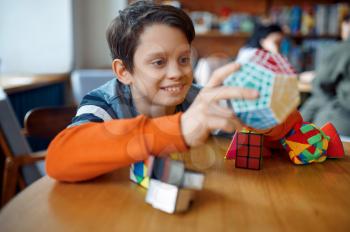 Smiling little boy play with colorful puzzle cubes. Toy for brain and logical mind training, creative game, solving of complex problems