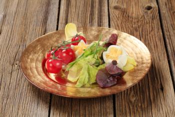 Fresh vegetables and boiled eggs on gold plate