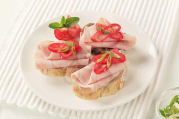 Open faced ham sandwiches garnished with red pepper