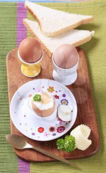 Three boiled eggs in porcelain eggcups and white bread