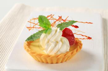 Custard tart topped with cream and raspberry