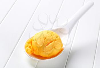 Scoop of yellow ice cream on porcelain spoon