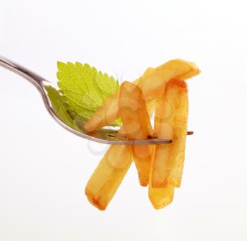 French fries on a fork against white background