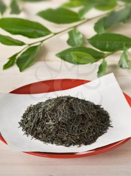 Heap of dried tea leaves on a red plate

