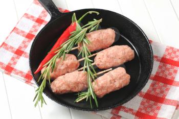 Raw minced meat kebabs on frying pan