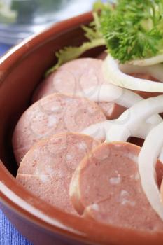Dish of sliced sausages and onion - detail