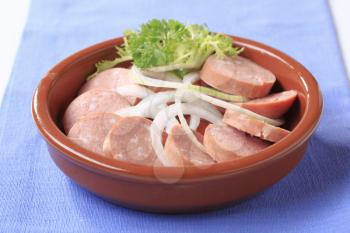 Dish of sliced sausages and onion - closeup
