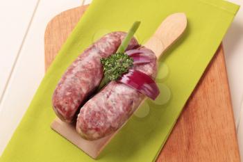 Italian sausages and Spanish onion on cutting board