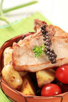 Juicy pork chop and potatoes in a terracotta bowl
