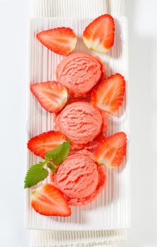 Scoops of strawberry ice cream on a long plate