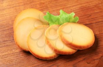 Slices of round artisan cheese on cutting board