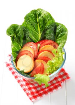 Slices of smoked cheese and tomato on lettuce leaves