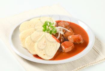 Pork meat in tomato sauce served with raised dumplings