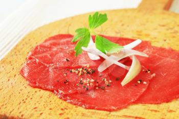 Thin slices of raw beef tenderloin on cutting board