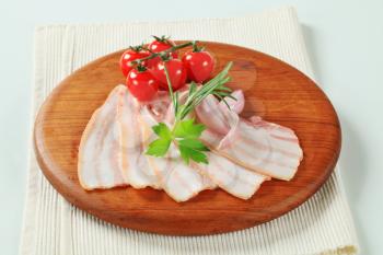 Thin slices of fresh pork belly on cutting board
