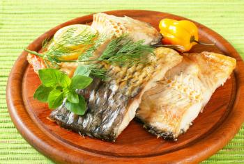 Oven-baked carp fillets on round cutting board