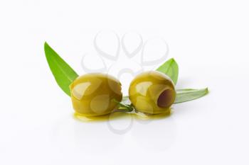 Two pitted green olives on white background