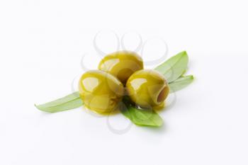 Three pitted green olives with fresh leaves