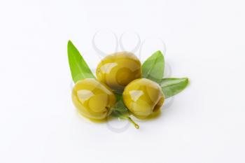 Three pitted green olives with fresh leaves