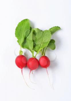 Three fresh red radishes on white background