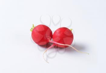 Two fresh red radishes on white background