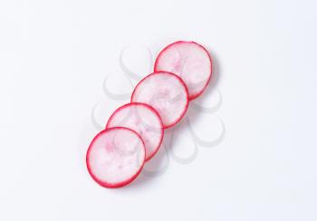 four thin slices of radish on white background
