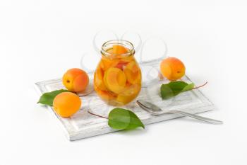 Jar of apricot compote and bowl of fresh apricots