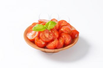 Halved red cherry tomatoes in terracotta bowl