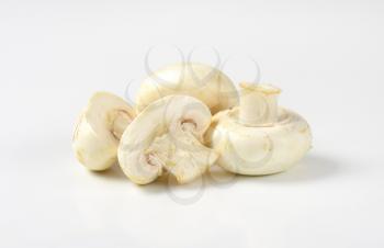 Whole and halved raw white mushrooms