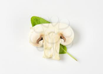 Slice of raw button mushroom and fresh sage leaf