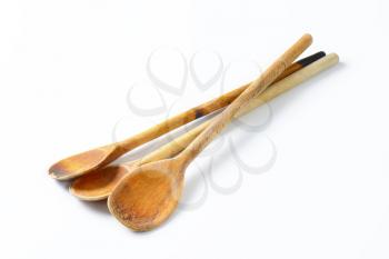 three old wooden spoons on off-white background