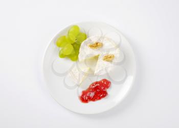 brie cheese with walnuts, grapes and jam on white plate