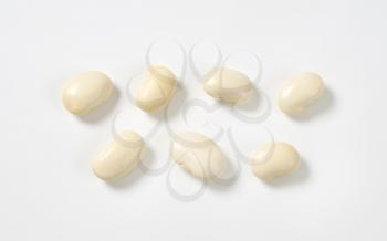 seven raw white beans on white background