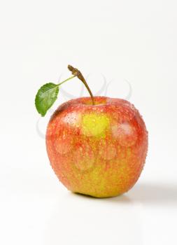washed red apple with leaf on white background
