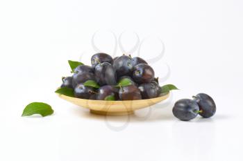 ripe plums on bamboo plate and next to it
