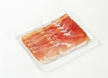 Thin slices of dry-cured smoked ham (Schwarzwald ham) on white background