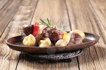 Beef shish kebab and new potatoes on cast iron plate
