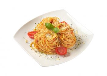 plate of cooked spaghetti with red pesto and grated parmesan cheese