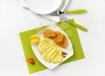plate of chicken nuggets with mashed potatoes on green place mat